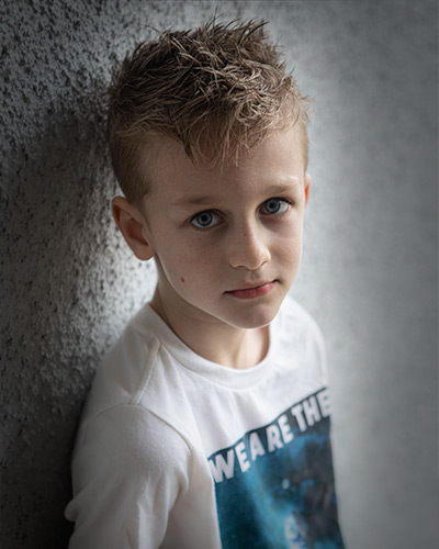 a headshot of a boy against a wall