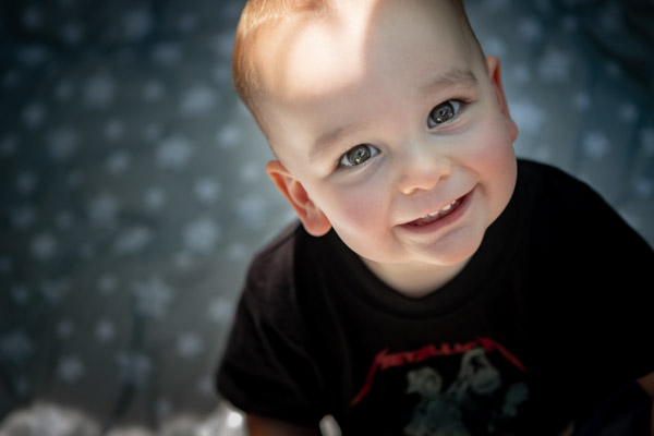 a toddler with a Metallica t-shirt looking up at the camera and smiling
